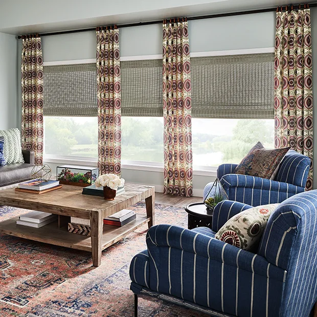Brown patterned drapes and gray shades on three living room windows