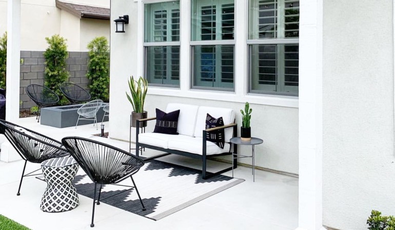 Spending a little time mulching and weeding can help give you an outside oasis. Backyard with plantation window treatments