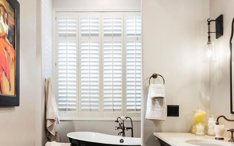 White Polywood shutters above a soaking tub.