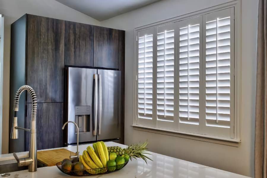 Homeowners use indoor window shutters in Salt Lake City when they want attractive and functional window treatments. Polywood shutters on a large kitchen window