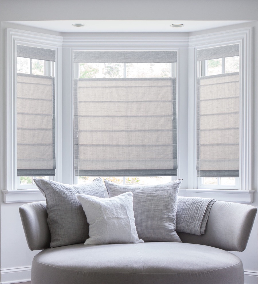 White Roman shades above a loveseat