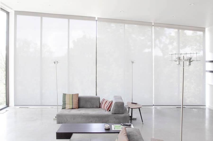 Motorized window shades make controlling natural light effortless in your Salt Lake City great room. White motorized shades on a wall of tall great room windows