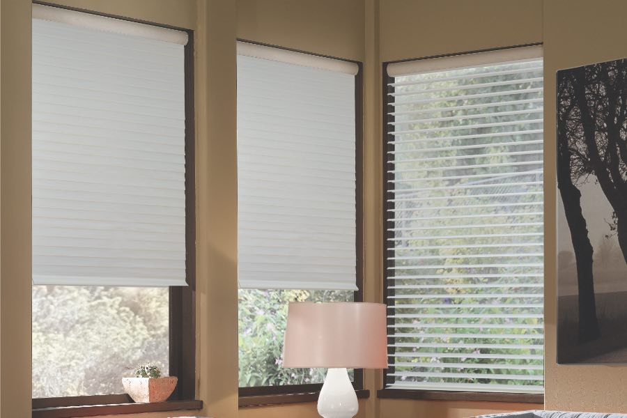 Opaque motorized window shades in Salt Lake City keep hot UV rays out of your home. Gray motorized sheer shades on corner windows next to gray furniture