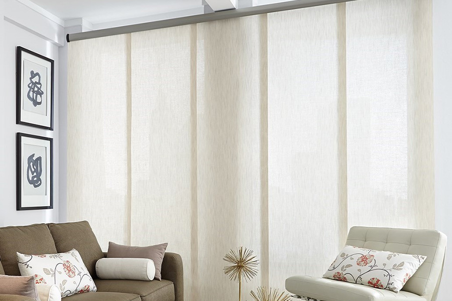 Find window treatments to complete any interior design among our extensive selection at Sunburst Shutters Salt Lake City.  Long off-white window shades on a tall window in a modern living room