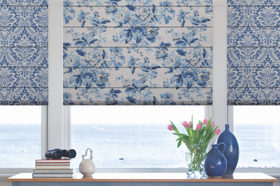 Beautiful new window treatments make windows even more eye-catching.  Blue and white patterned Roman shades on a window overlooking the ocean
